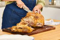 A person carving a KellyBronze Turkey on a cutting board
