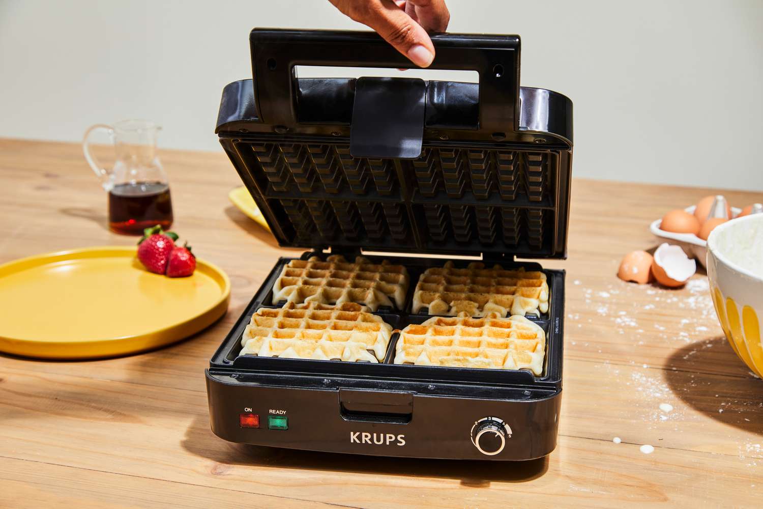 A Krups waffle maker containing 4 cooked waffles