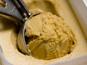 Closeup of carrot cake ice cream being scooped from a storage container.