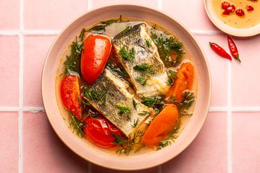 Overhead view of soup on a pink, titled background