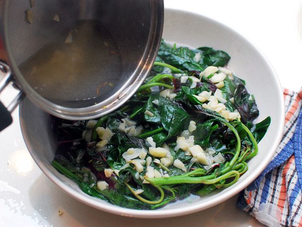 Pouring garlicky broth over braised spinach and red shen choy.