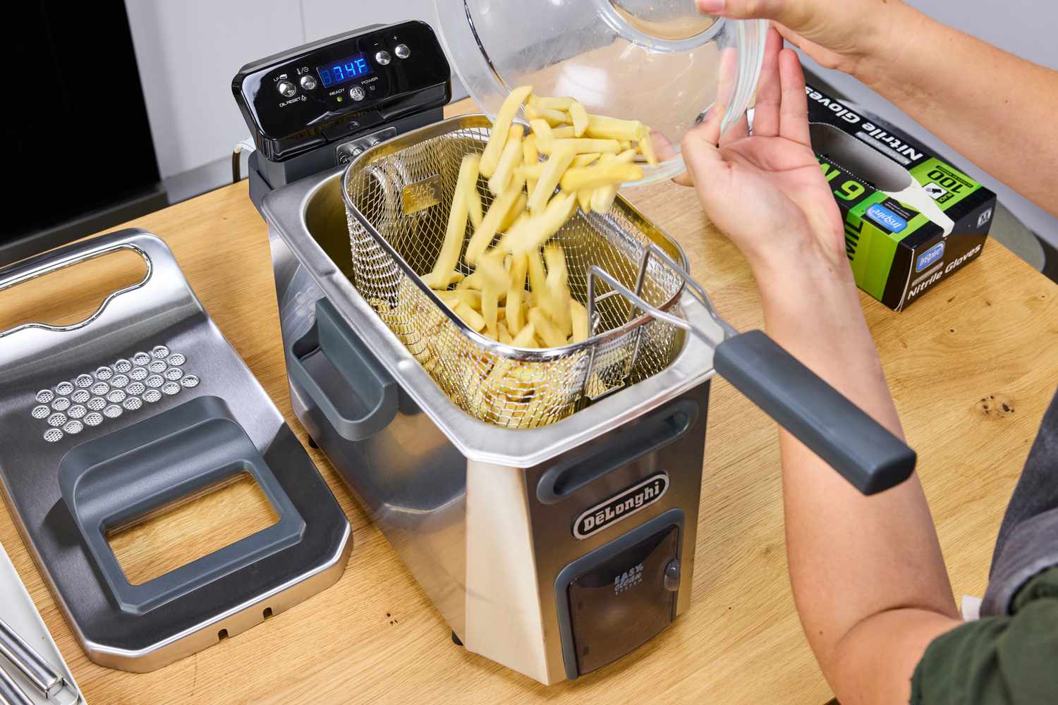 A person pours frozen fries into the DeLonghi D44528DZ Livenza Deep Fryer