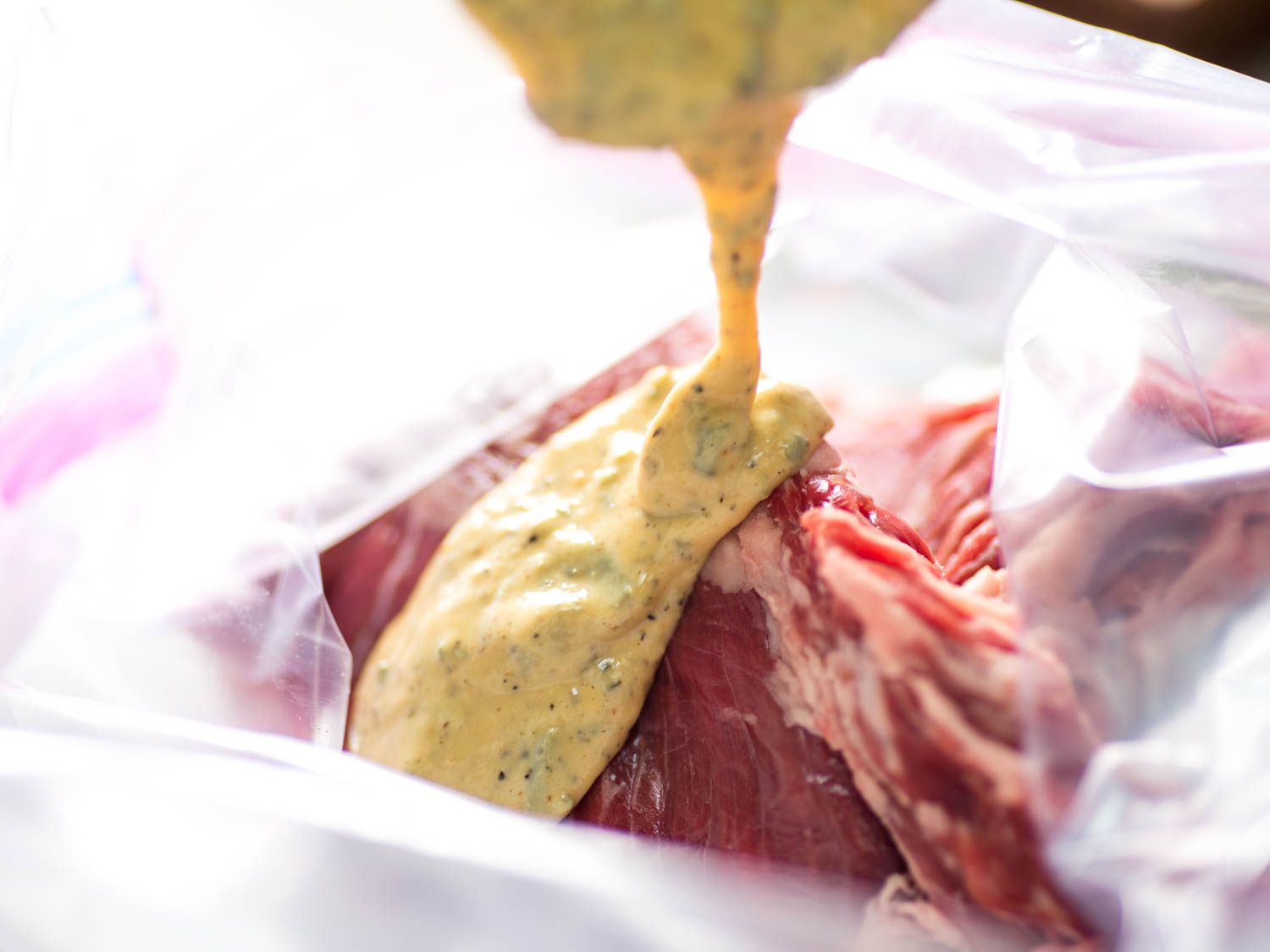 The Dijon marinade is poured into a zip-top bag along with several skirt steaks.