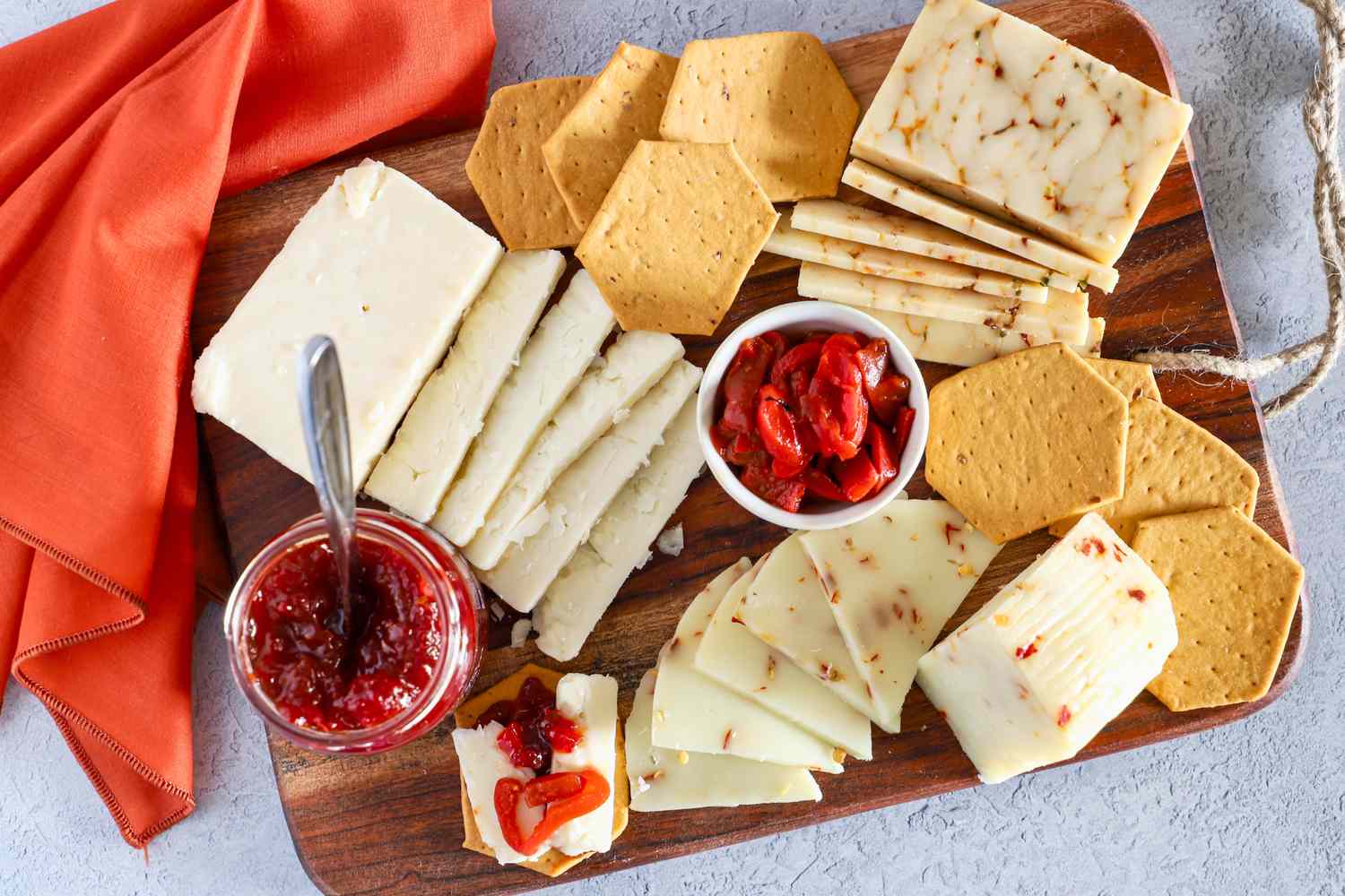 Cheese slices, crackers and condiments from Curdbox Cheese Subscription Box arranged on a wooden board