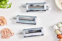 Three attachments of the KitchenAid 3-Piece Pasta Roller & Cutter Attachment Set displayed on white surface 