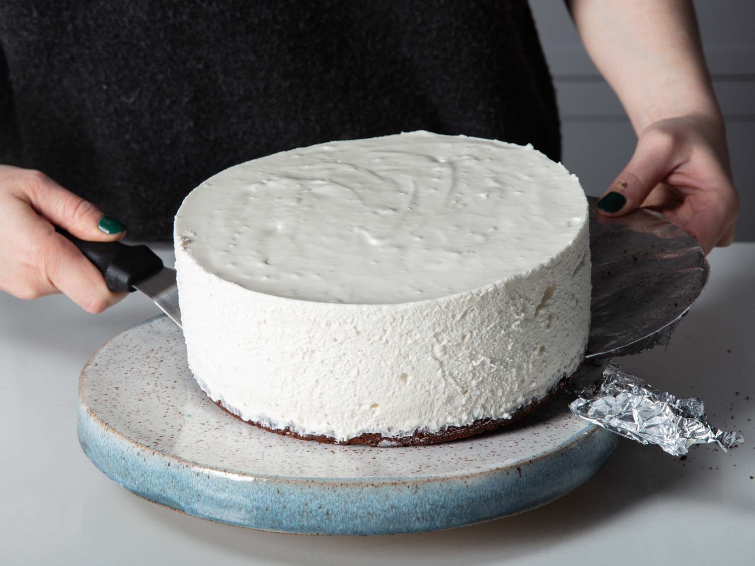 Sliding the no-bake cheesecake onto a cake stand.