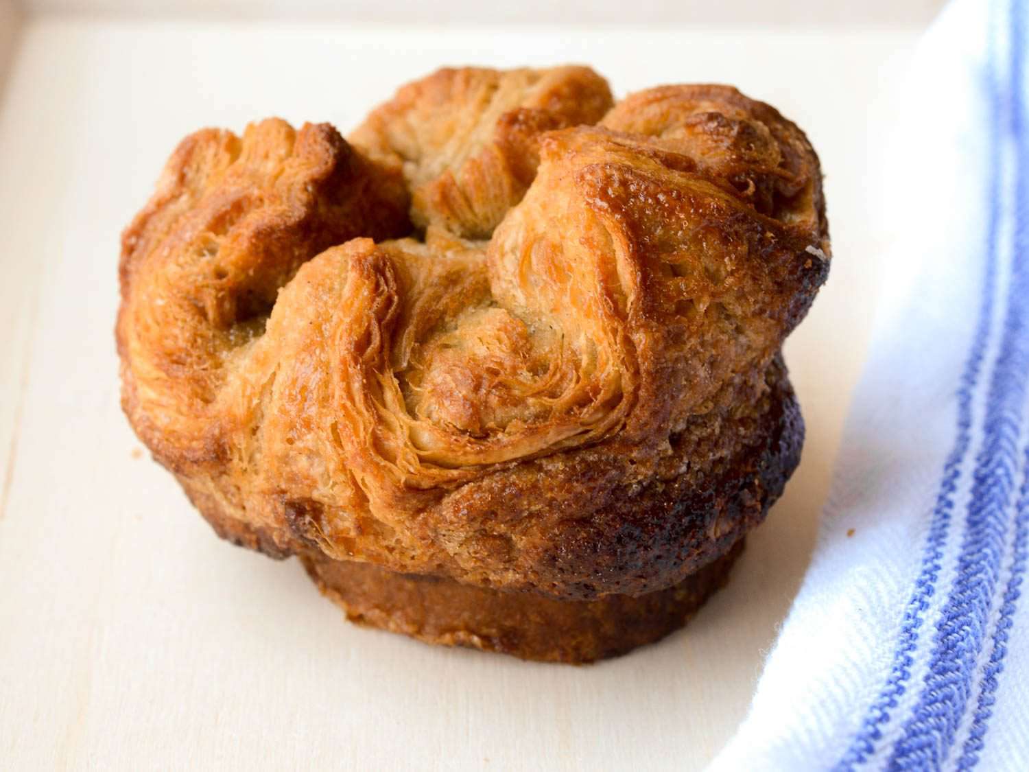 Overhead of kouign amann on white towel with blue stripe.