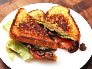 A vegan B.L.A.T. sandwich halved and served on a white plate.