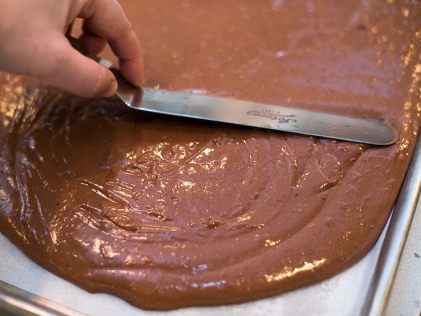 Cake batter is spread evenly in the jelly roll pan with an offset spatula.