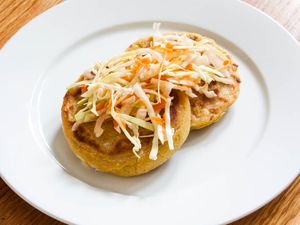 Two cheese and bean pupusas topped with cabbage slaw