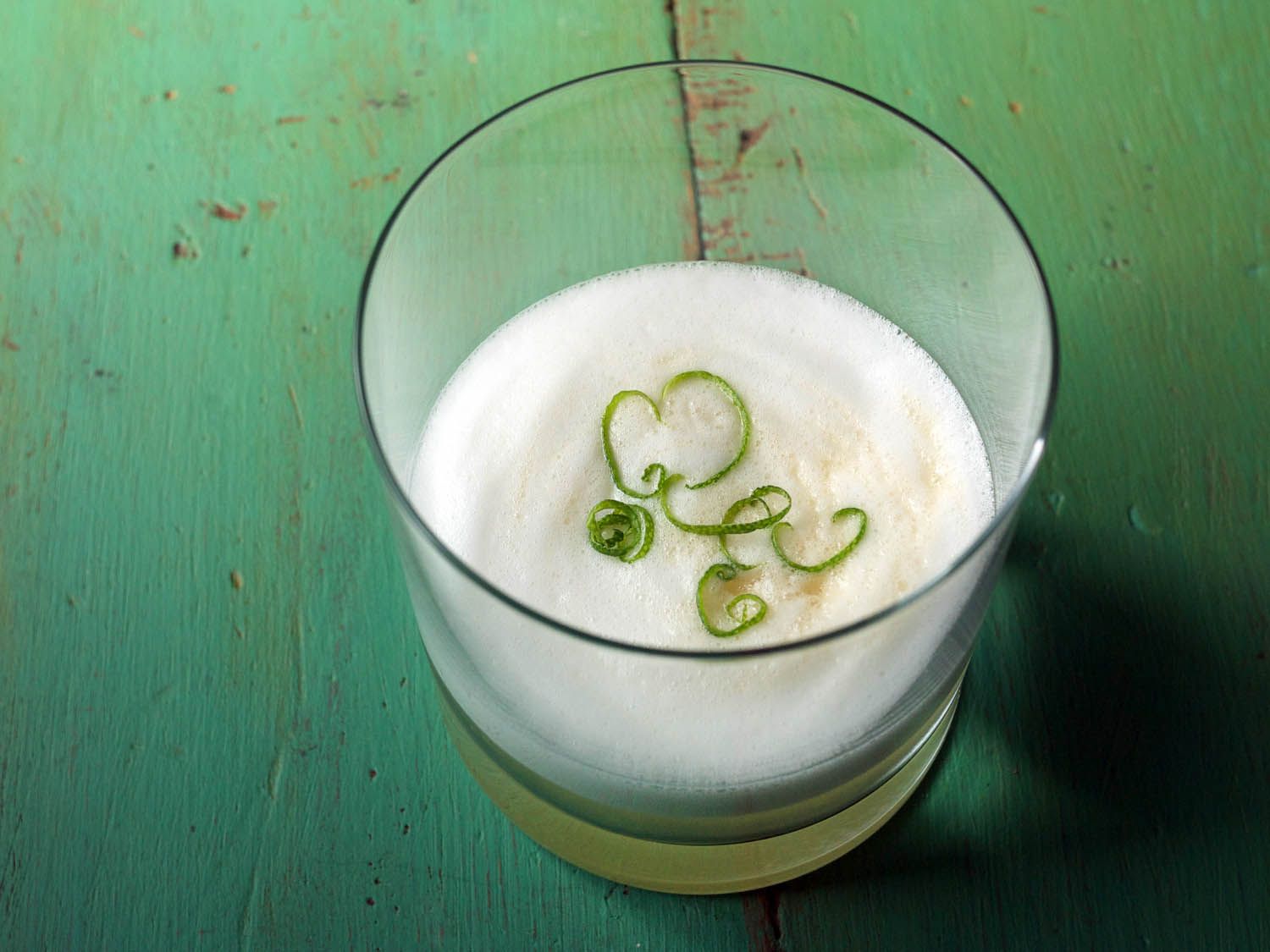 Closeup of a finished lemongrass sour with lime zest garnish.
