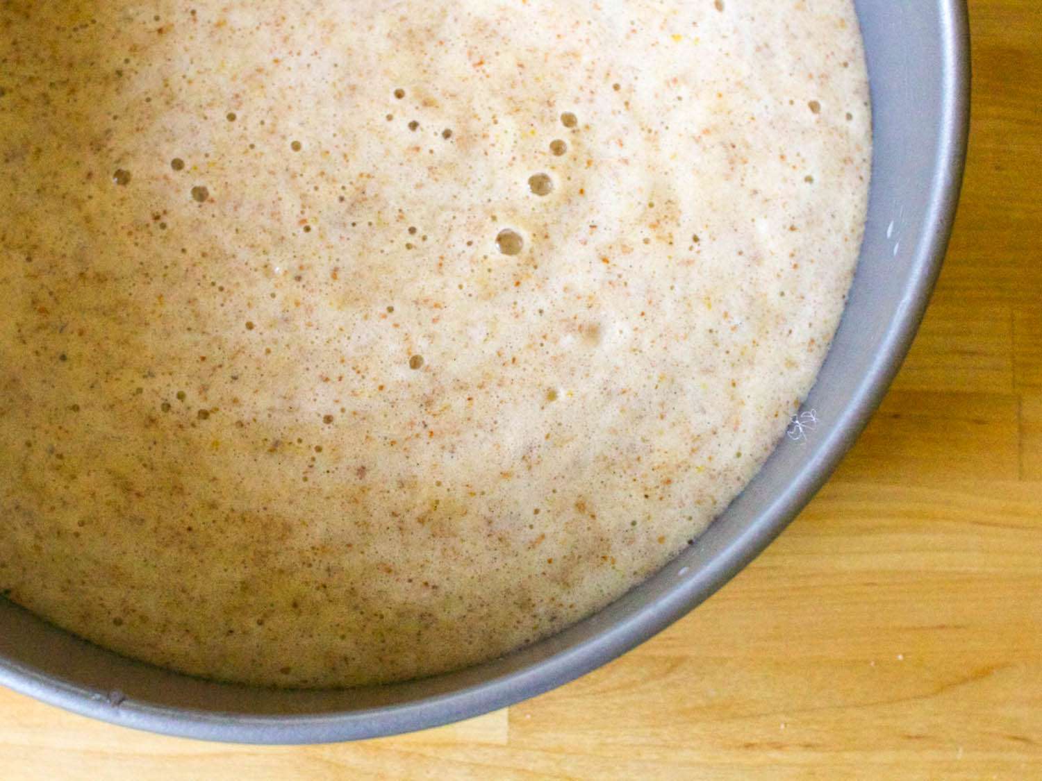 A greased cake pan with airy batter inside of it.