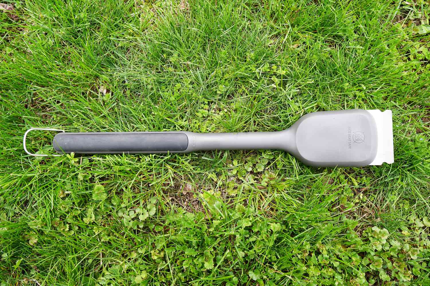 an oxo grill brush laying on the grass