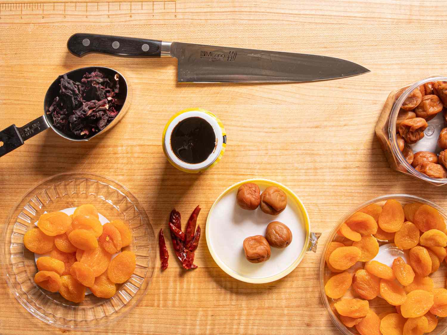 A cutting board with common chamoy ingredients on it: hibiscus, apricots, chiles