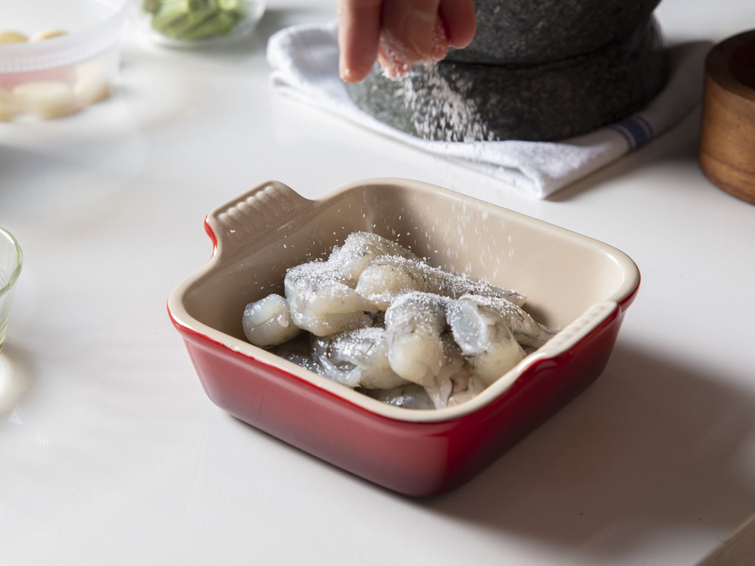 Shrimp in a square red bowl being sprinkled with mixture