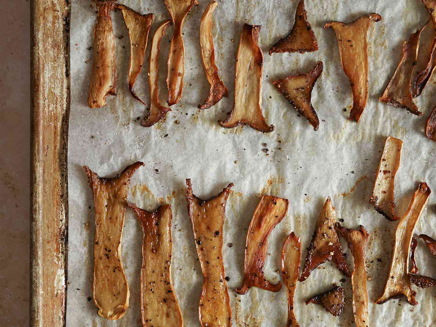 Crisp and well-browned mushrooms on lined rimmed baking sheet after coming out of oven.