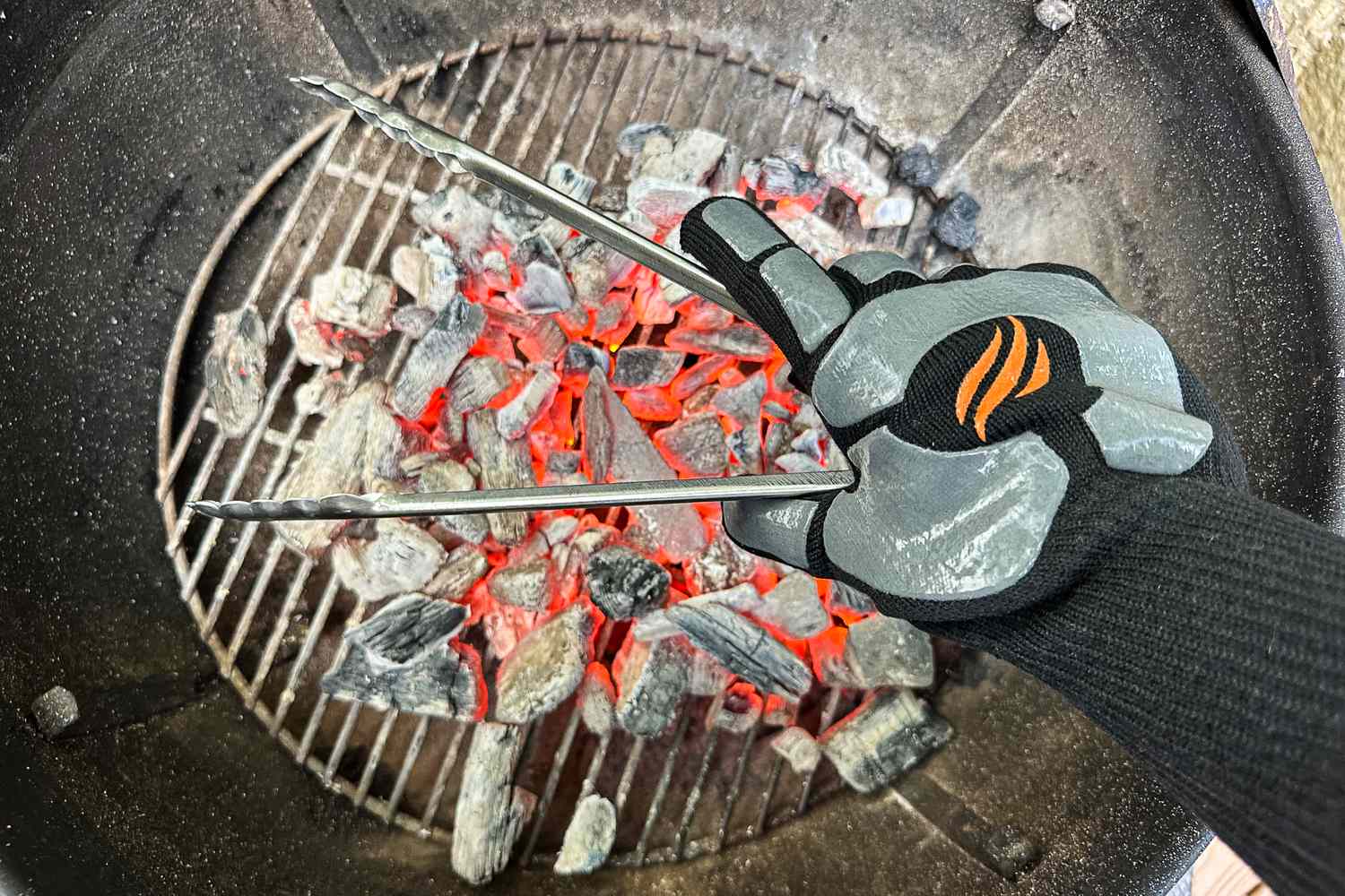 A person holds a pair of tongs while wearing the Blackstone Griddle Gloves