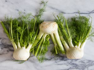 Three fennel bulbs on a marble surface