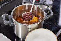 A person ladles beans from the T-Fal Clipso Pressure Cooker