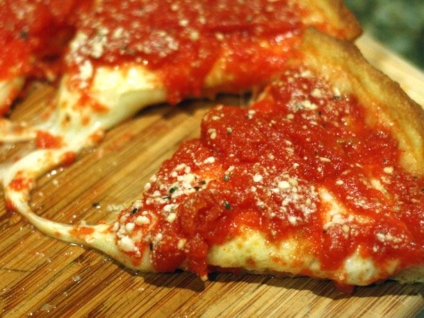 Frozen deep dish pizza cut into wedges on a cutting board 