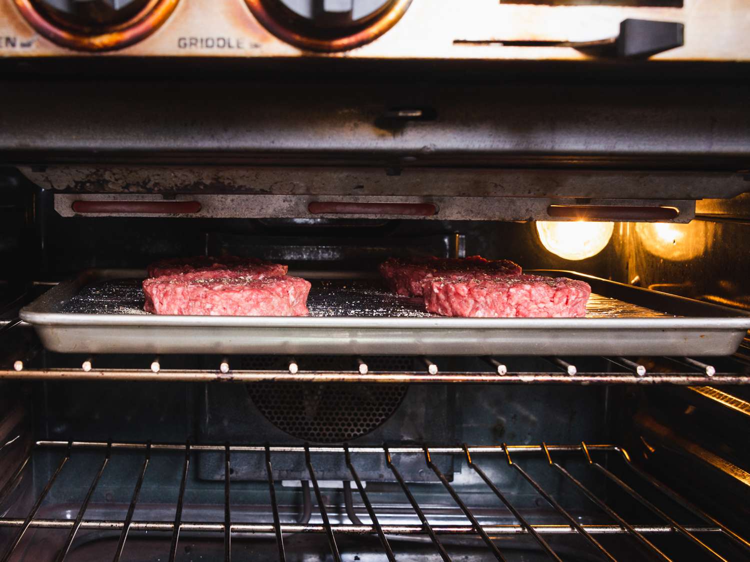 burgers on a baking sheet under the broiler