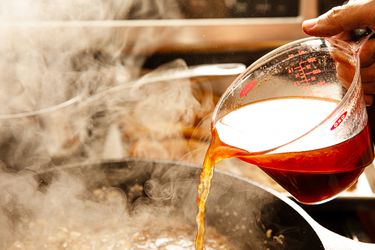 Chicken stock being poured into a pan.