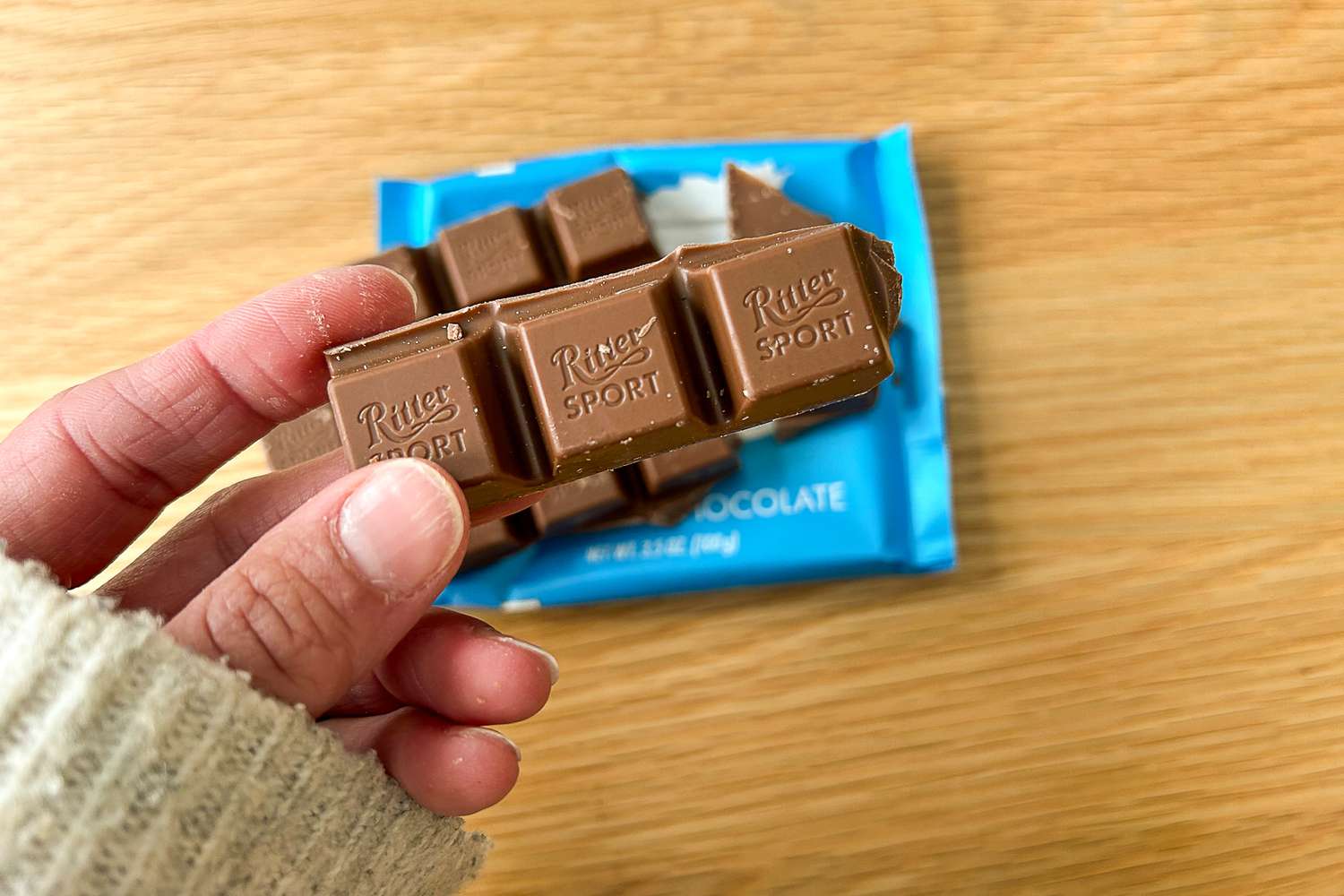 A person holding pieces of Ritter Sport Alpine Milk Chocolate