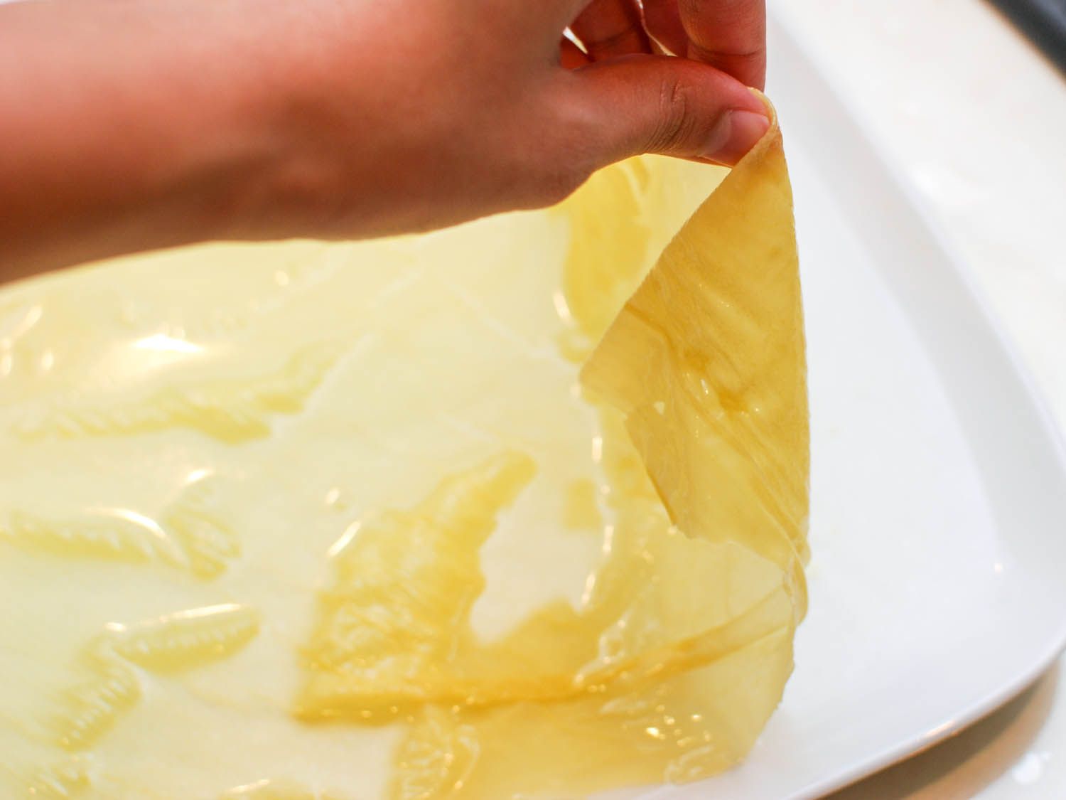 Author lifting an edge of a rehydrated bean curd sheet to show its pliability, fragility.