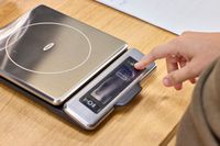 A person presses a button on the OXO Good Grips Stainless Steel Food Scale with Pull-Out Display