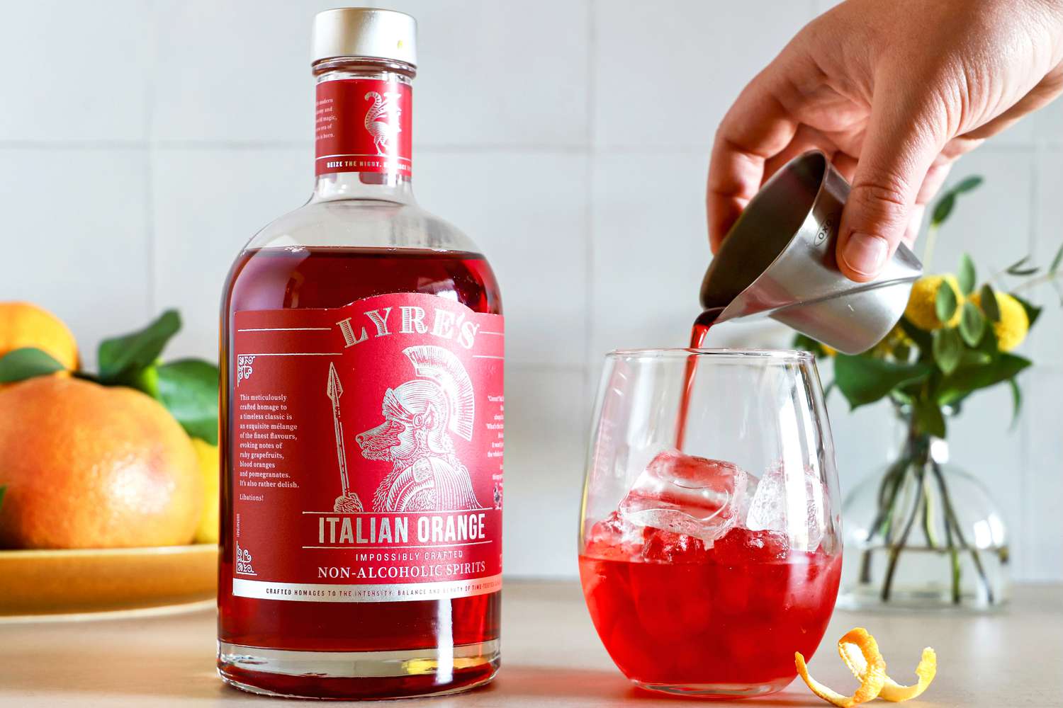 A person pouring a nonalcoholic mixer into a glass with ice.