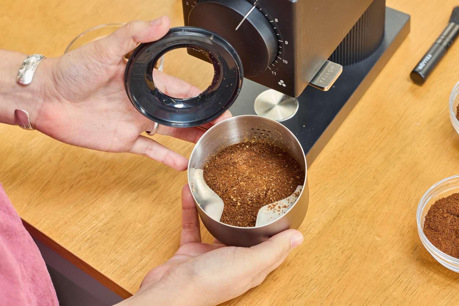 A person holds up a can of coffee ground in the Fellow Ode Gen 2 Coffee Grinder