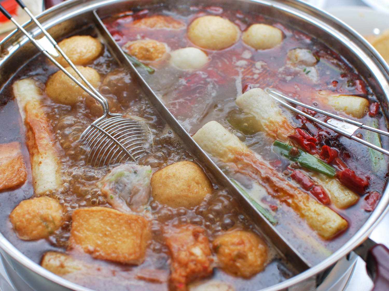 Chinese hot pot filled with simmering broth, fish balls, tofu, and vegetables