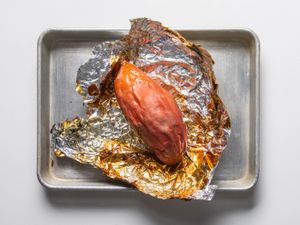 Frozen roasted sweet potato on foil in a rimmed baking sheet