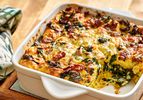 Kale and bacon strata in a baking dish with one portion removed