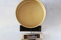 The OXO kitchen scale with an empty cake pan on it.