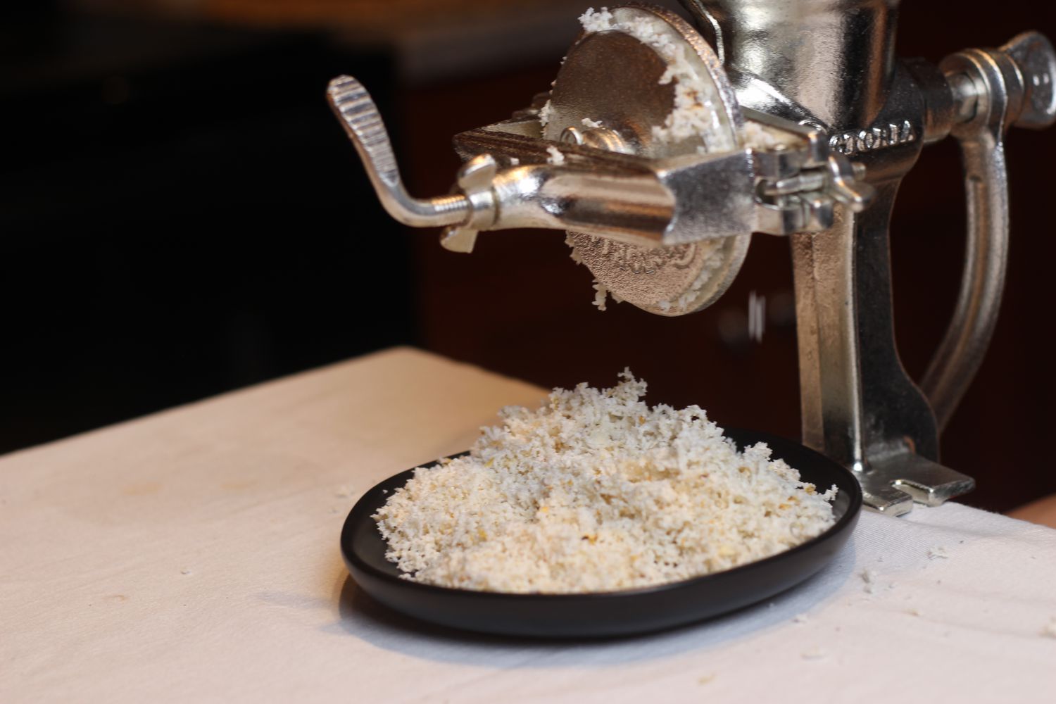 ground masa coming out of the mill onto a black dish