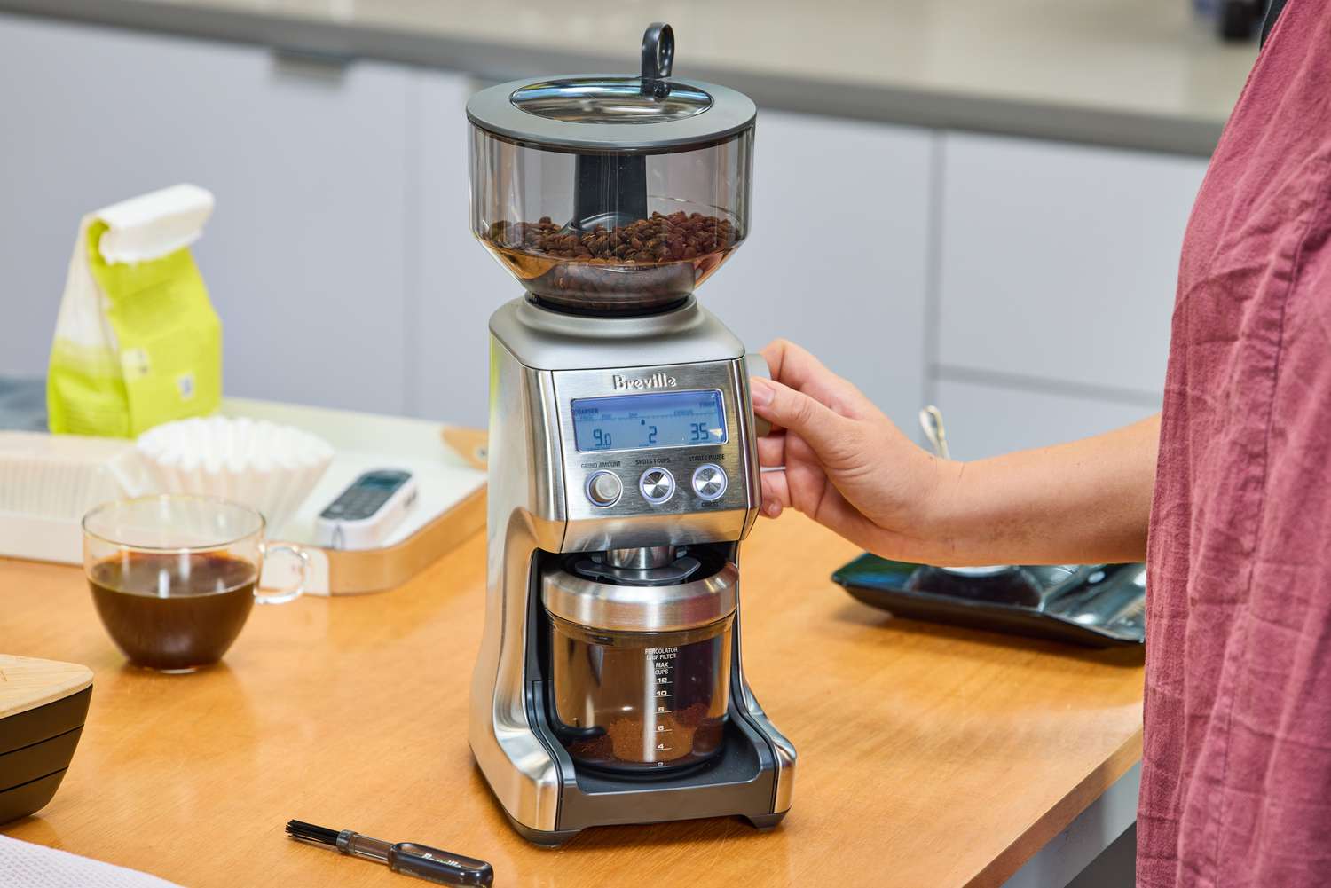 A person grinds coffee beans in the Breville The Smart Grinder Pro
