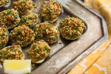 A tray of easy, ultimate Clams Casino with a lemon wedge. 
