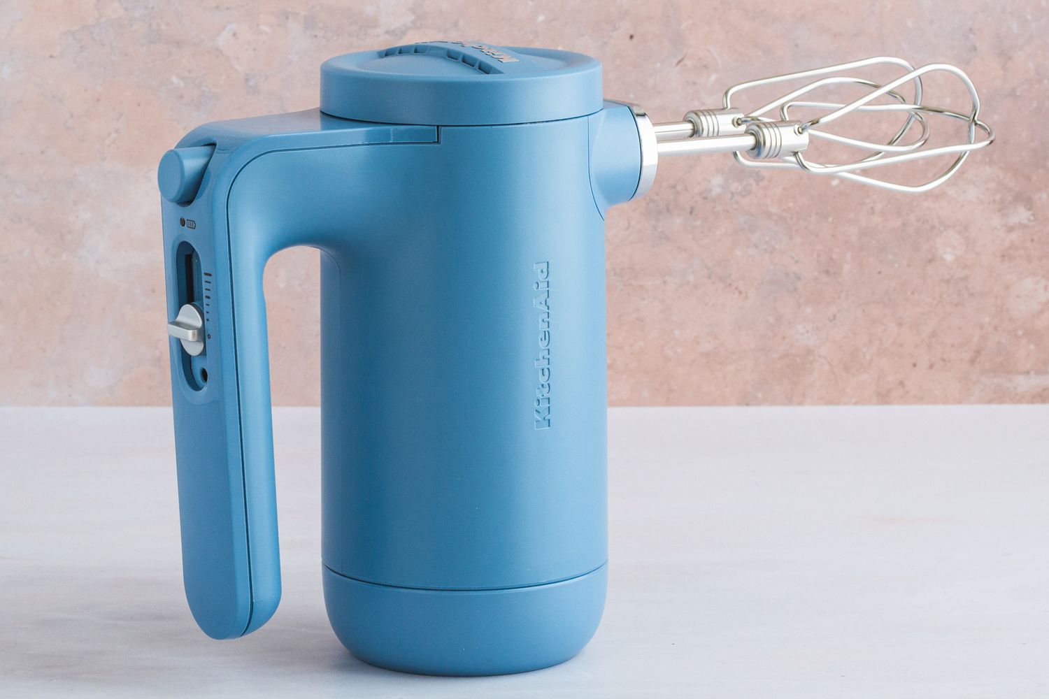 A blue, cordless KitchenAid hand mixer.