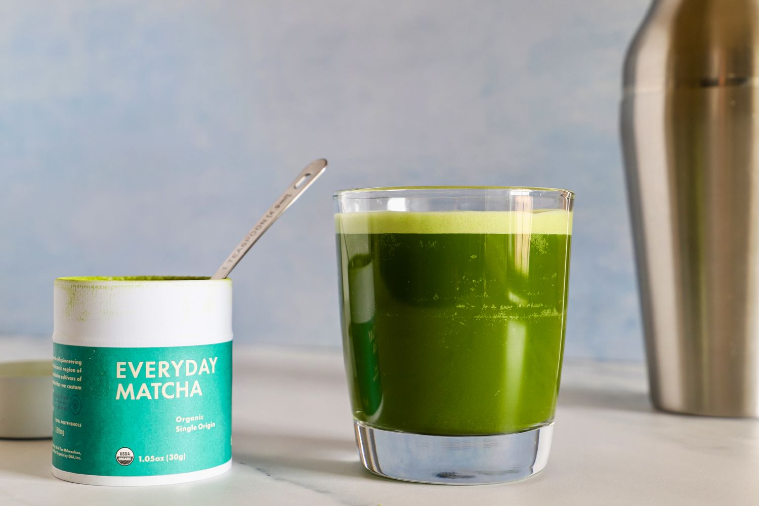 A glass of Rishi Tea Everyday Matcha next to the container