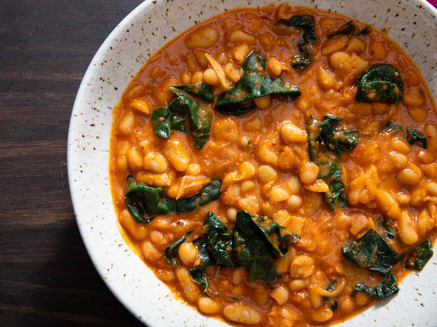 Closeup overhead of a bowl of white bean and kale stew with 'nduja.