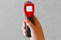 A person holding the Wintact infrared thermometer.