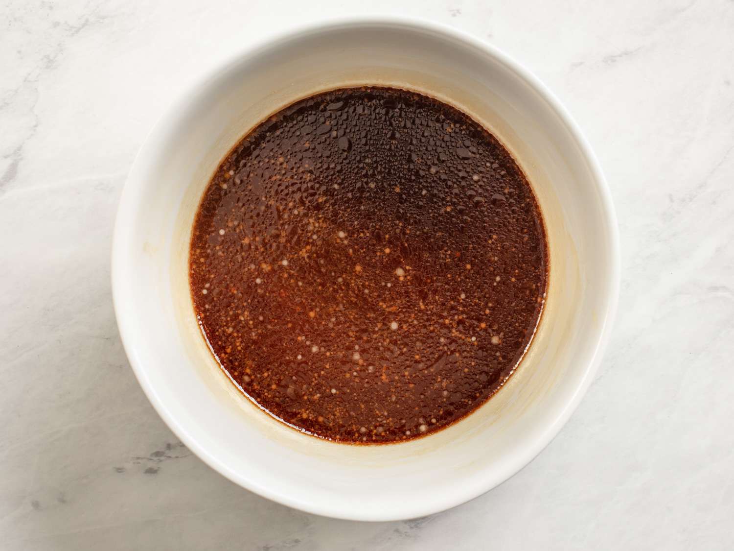 Kung pao chicken sauce (chicken stock, soy sauce, wine, vinegar, sugar, cornstarch, and sesame oil) in a white bowl.