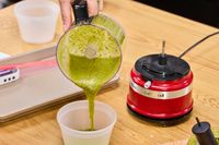 a person pours pesto from a food processor