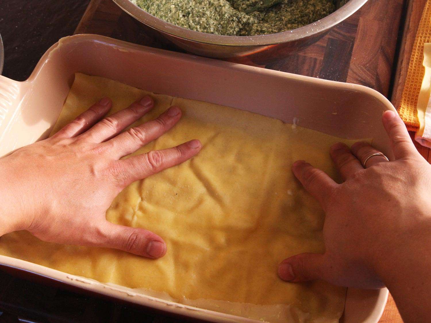 Laying down the first layer of pasta over white sauce