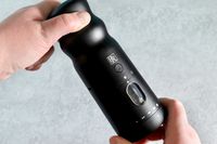 a person turning the dial on the black rain pepper mill