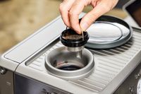 Closeup of a person lifting up one section of the Breville Barista Express Impress