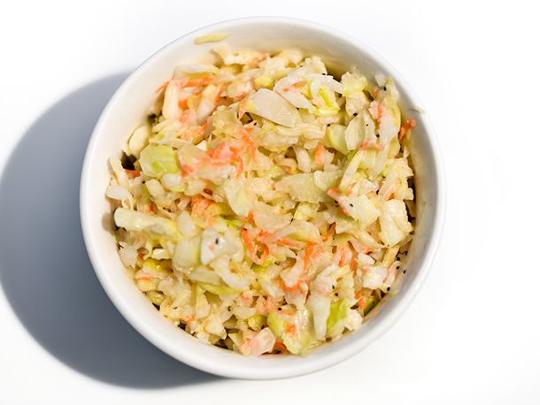 Tangy apple coleslaw, served in a white bowl on a white background.