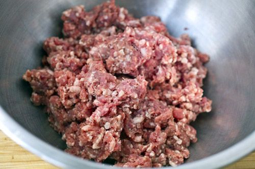 Raw, ground hamburger in a stainless steel bowl.