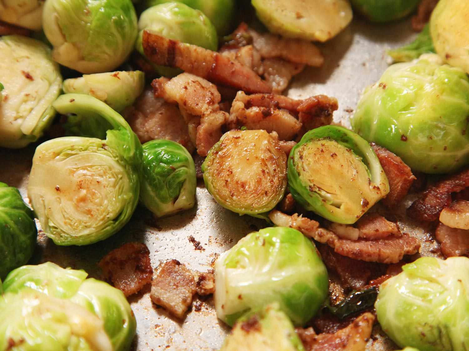 Lightly browned Brussels sprouts and bacon on baking sheet